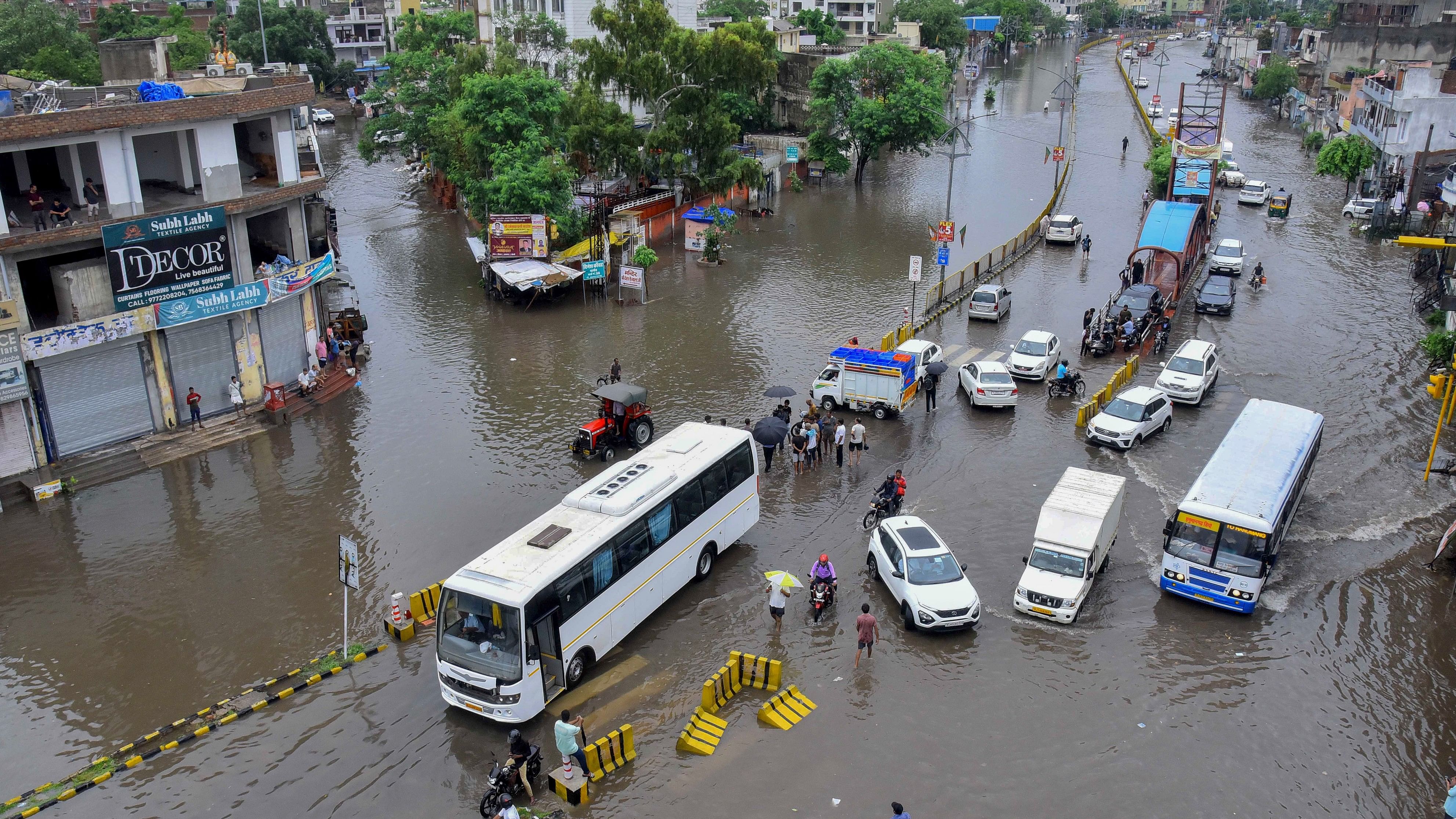 <div class="paragraphs"><p>Commuters wade through a waterlogged road after rains, in Jaipur.</p></div>